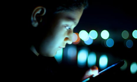 kid looks at phone in the dark