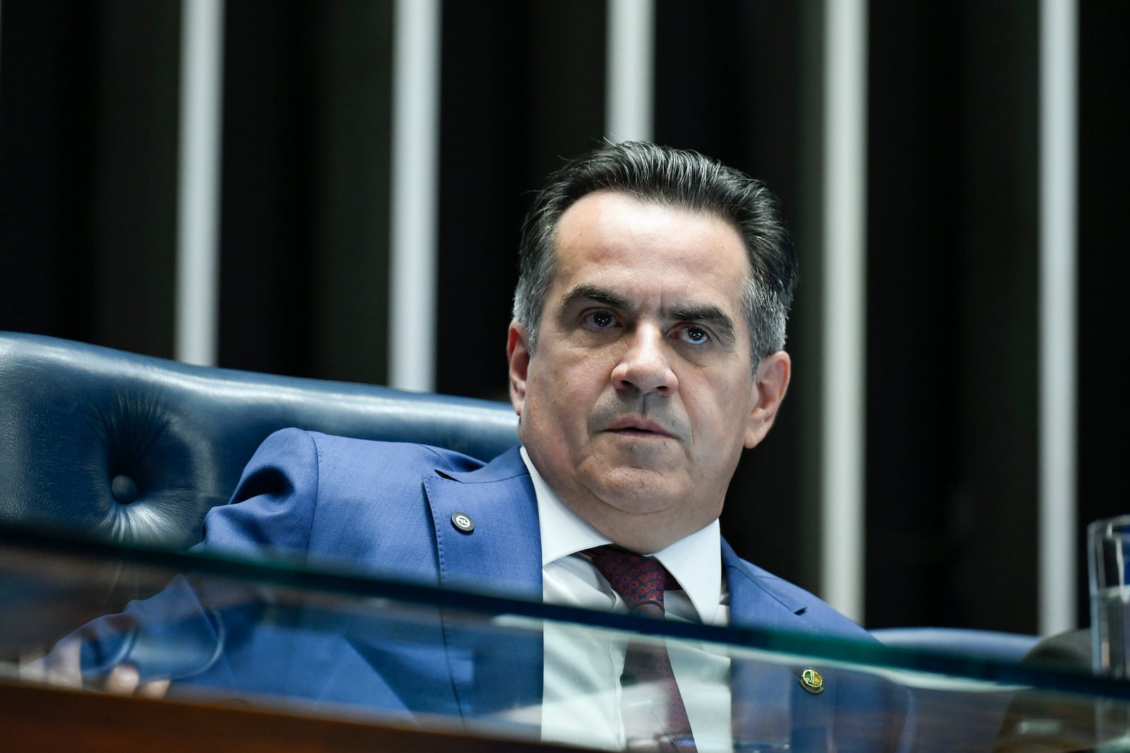 Homem de terno, no Senado, observa com olhar desconfiado