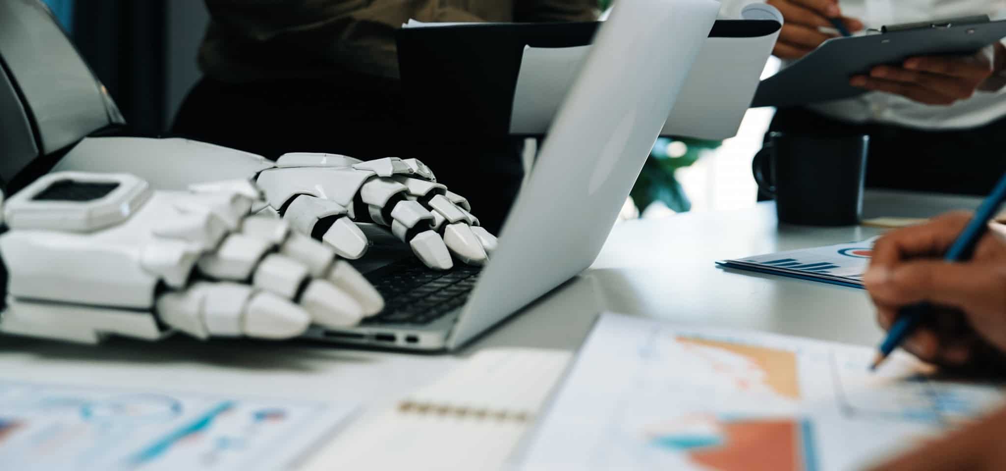 imagem mostra a mão de um robô digitando em um teclado de computador. imagem representa inteligência artificial e robôs no mercado de trabalho